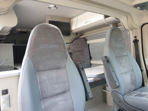 Wnętrze kampera z dwoma obrotowymi fotelami i stołem