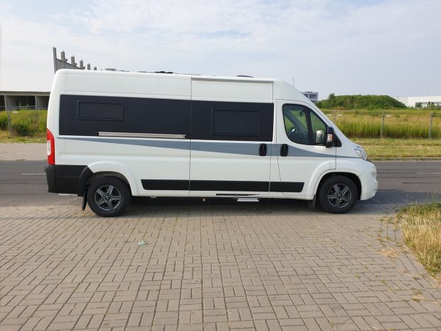 Biały kamper zaparkowany na chodniku, boczny widok