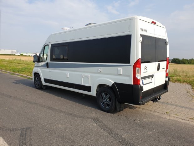 Biały kamper Citroën z przyciemnionymi oknami zaparkowany przy polnej drodze