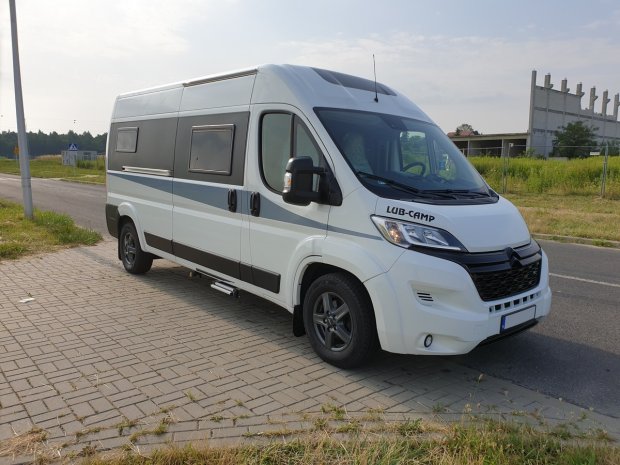 Biały kamper LUB-CAMP zaparkowany na chodniku przy drodze, widok z przodu i boku