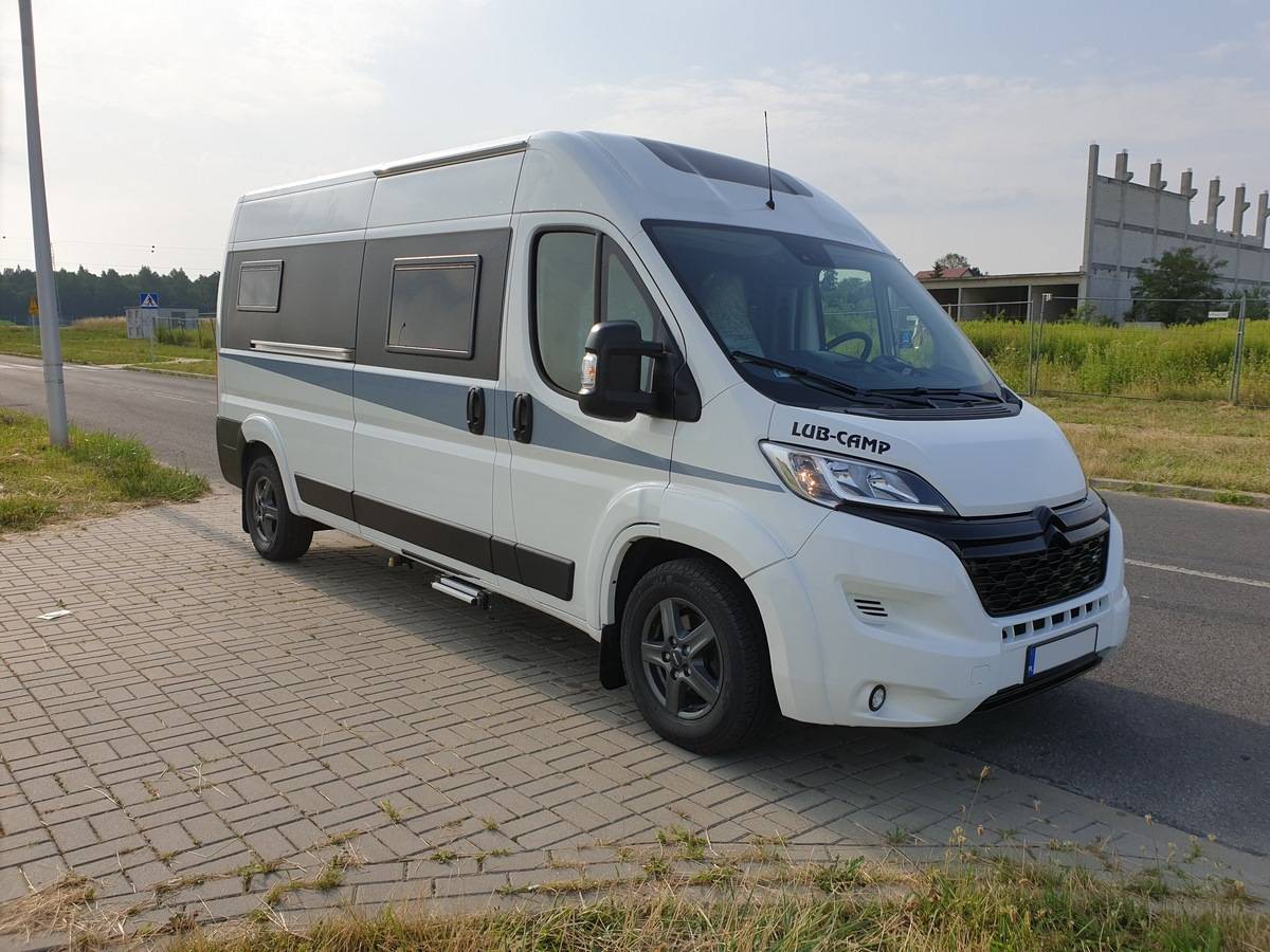 Biały kamper LUB-CAMP zaparkowany na chodniku przy drodze, widok z przodu i boku