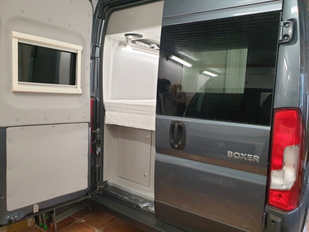 Otwarty tył vana Boxer z wnętrzem kempingowym i łóżkiem.