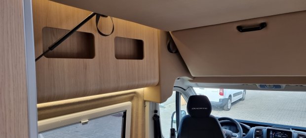 Wnętrze kampera z drewnianą półką nad kabiną i fotelem kierowcy 'Ducato'.