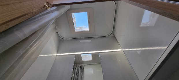 Okno dachowe w kamperze z lustrzaną ścianką, zasłoną i paskiem LED