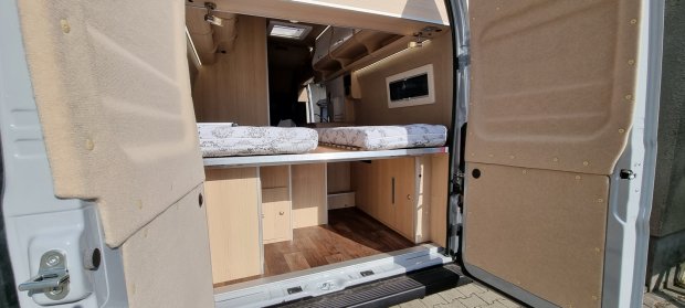 Tył kampera z rozłożonym łóżkiem i przestronnymi schowkami