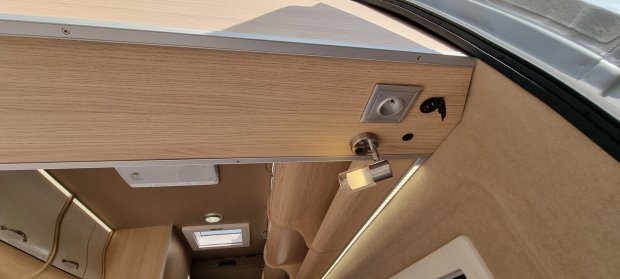 Sufit i szafki wnętrza kampera z drewnianymi panelami, lampką i gniazdkiem