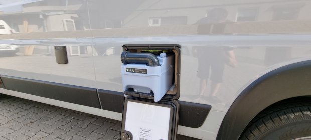 Wysunięty kasetowy zbiornik toalety w otwartej skrytce boku kampera