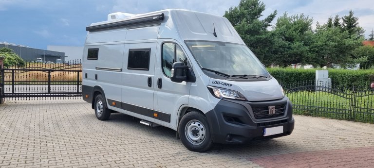 Szary kamper Fiat LUB-CAMP zaparkowany przed metalową bramą