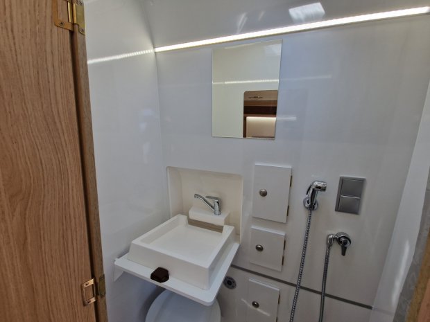 Mała łazienka kempingowa z rozkładanym zlewem, prysznicem ręcznym i lustrem