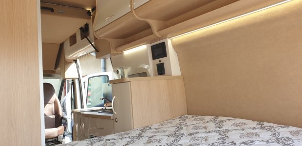 Wnętrze kampera: łóżko, aneks kuchenny, drewniane półki i podświetlenie LED.