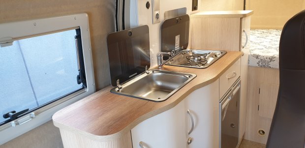 Kompaktowa kuchnia kampera z drewnianym blatem, zlewem i dwupalnikową kuchenką