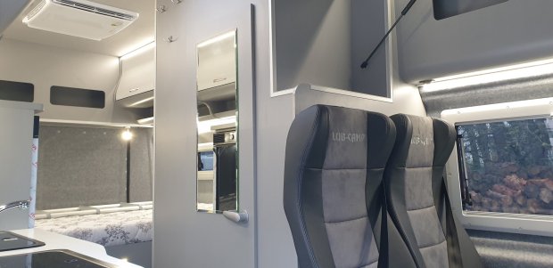 Wnętrze kampera z dwoma fotelami LUB-CAMP, łóżkiem i kuchenką