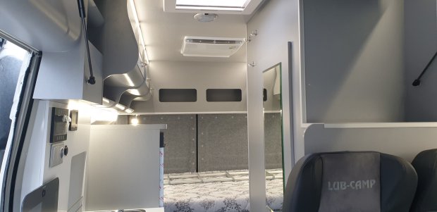 Wnętrze kampera z łóżkiem, schowkami, klimatyzacją i fotelem LUB-CAMP.