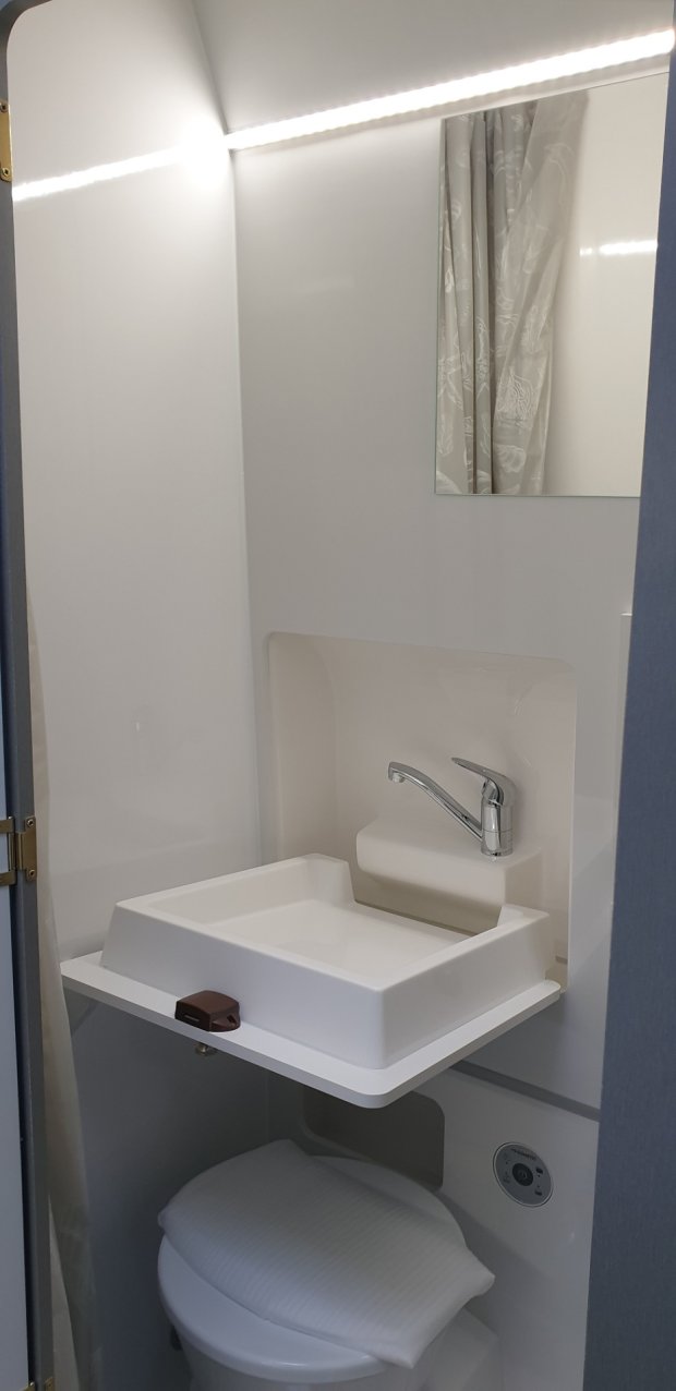 Kompaktowa łazienka z białą umywalką, chromowaną baterią i toaletą pod spodem