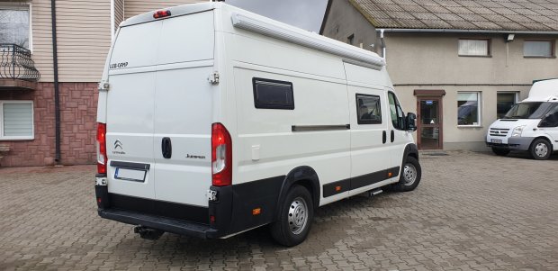 Biały kamper (Citroën Jumper) zaparkowany obok budynku na kostce brukowej.