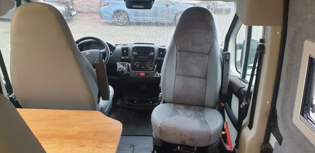 Wnętrze kampera: przednie fotele obrotowe, kierownica, stolik i deska rozdzielcza.