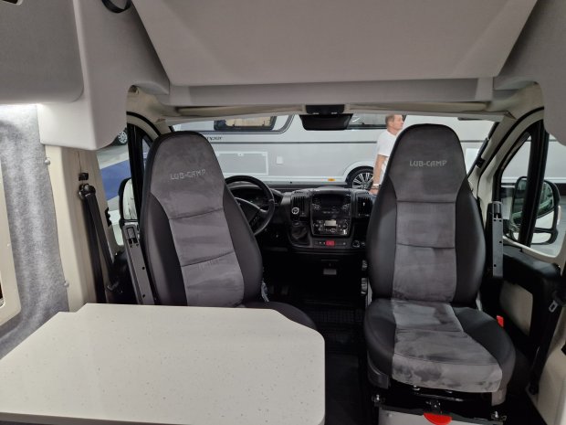 Wnętrze kampera: dwa obrotowe fotele LUB-CAMP i stolik przed nimi.