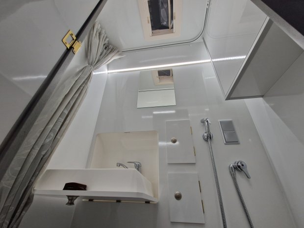 Białe, kompaktowe wnętrze łazienki z umywalką, prysznicem i zasłoną.