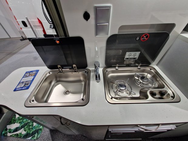 Kuchnia kampera: stalowy zlewozmywak po lewej i dwupalnikowa kuchenka po prawej.