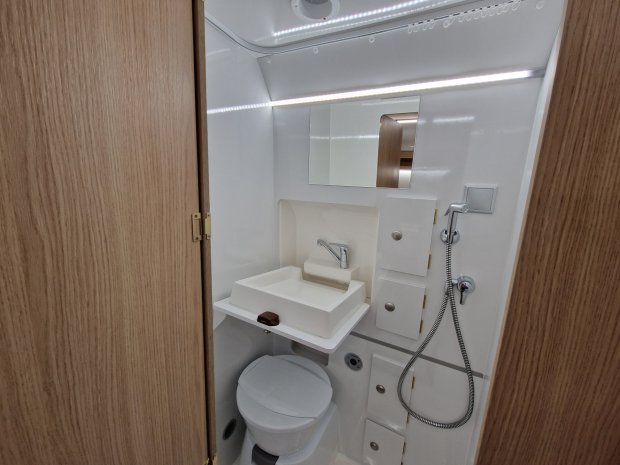 Mała łazienka kamperowa z toaletą, umywalką, lustrem i prysznicem na wężu