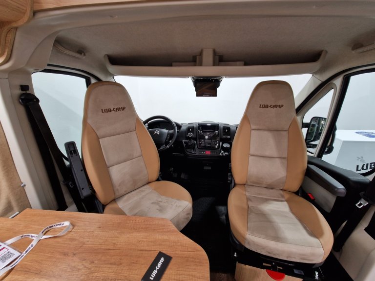 Wnętrze kampera: dwa obrotowe fotele LUB-CAMP i drewniany stół.