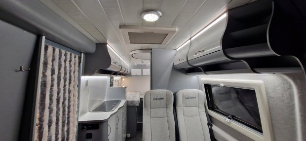 Wnętrze kampera: dwa fotele, kuchenka, szafki i oświetlenie LED