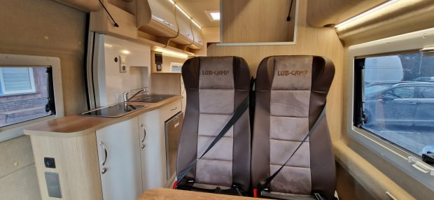 Wnętrze kampera z dwiema brązowymi fotelami LUB-CAMP i aneksem kuchennym