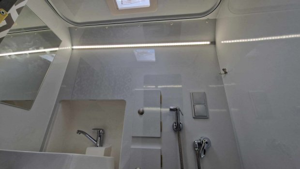 Jasna łazienka w kamperze z umywalką, chromowaną baterią i prysznicem ręcznym