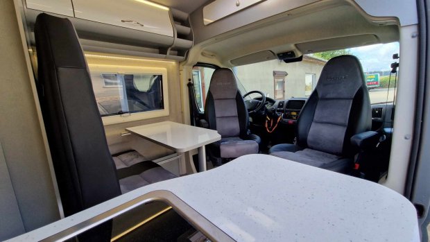 Wnętrze kampera: obrotowe fotele przednie, stolik i blat kuchenny