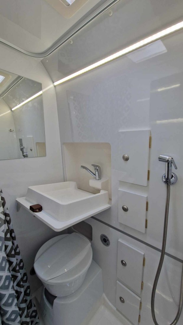 Kompaktowa łazienka kampera: toaleta, wysuwana umywalka, prysznic i szafki.